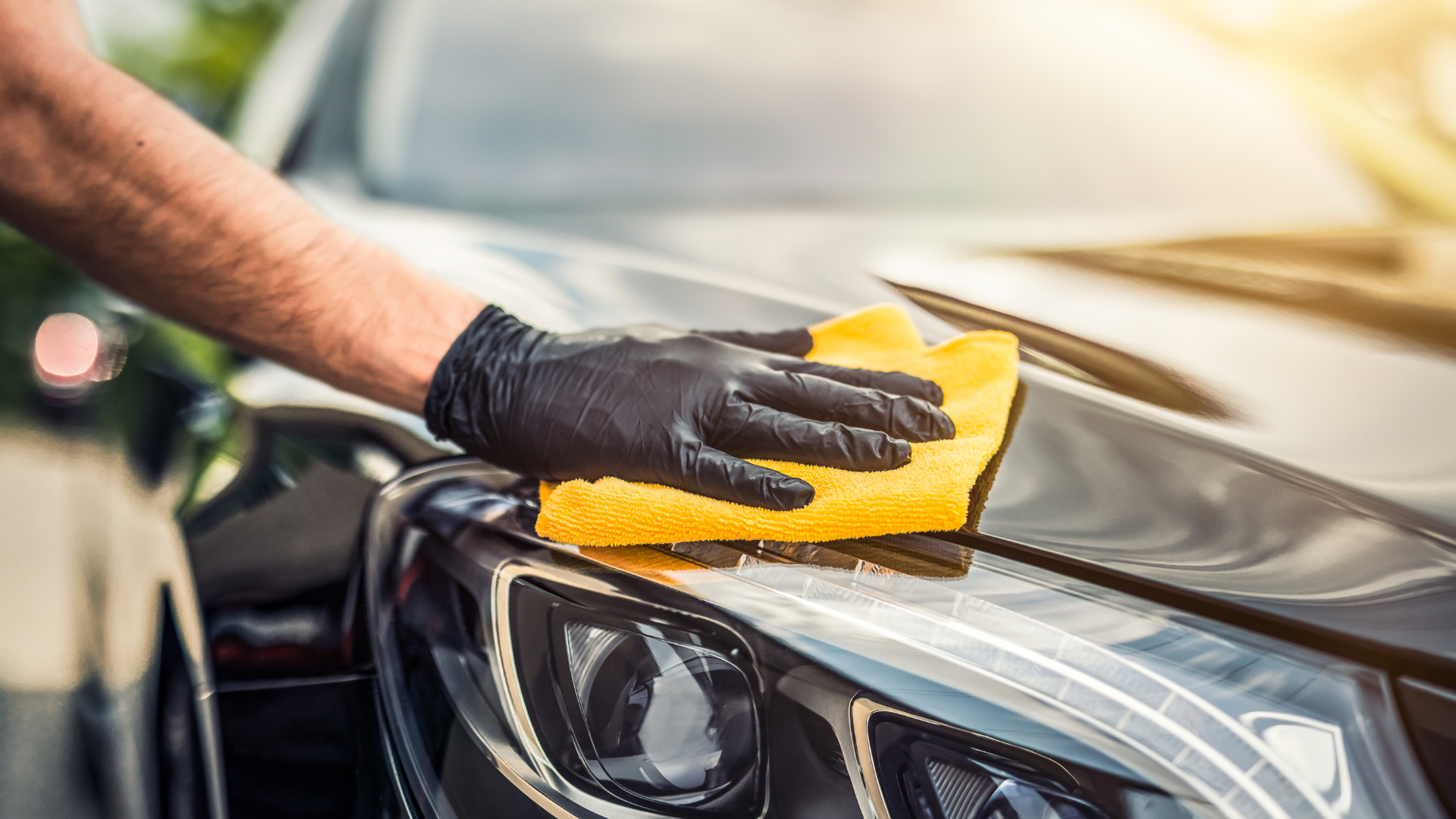 A hand applying wax on a car for a shiny finish